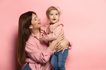 Play. Portrait of young woman and little girl, mother and daughter isolated on pink studio background. Mothers Day celebration. Concept of family, childhood, motherhoodの写真素材