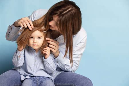 Studio shot of beautiful happy woman and little kid, mother and daughter isolated on blue...