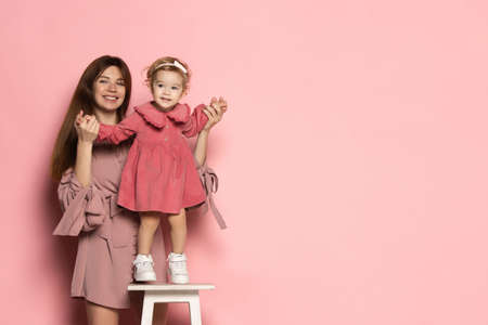 Emotional woman and little girl, caring mother and daughter isolated on pink studio background. Mothers Day celebration. Concept of family, childhood, motherhoodの写真素材