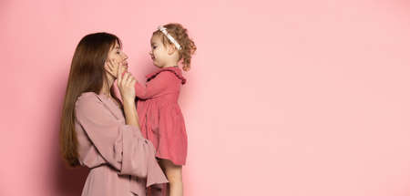 Delighted young woman and toddler, caring mother and daughter isolated on pink studio background. Mothers Day celebration. Concept of family, childhood, motherhoodの写真素材