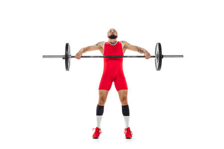 Full length portrait of man in red sportswear exercising with a weight isolated on white background....