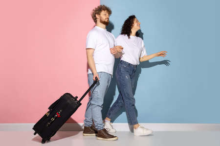 Married couple, young emotive man and girl goint on vacation isolated on blue and pink trendy color background. Relationships, travel, holiday conceptの写真素材