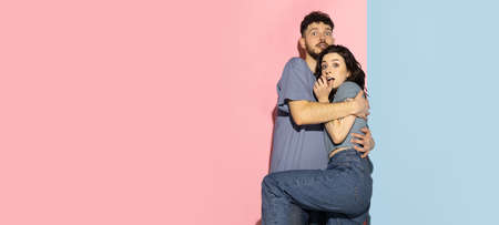 Portrait of young emotional man and girl isolated on blue and pink trendy color background. Human emotions conceptの写真素材