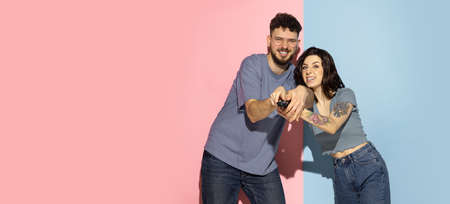 Portrait of young emotional man and girl isolated on blue and pink trendy color background. Human emotions conceptの写真素材