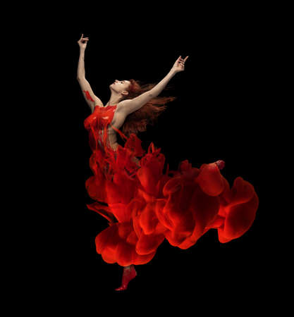 Firebird. Portrait of young tender woman covered with red paint and dye splah dancing isolated over black backgroundの写真素材