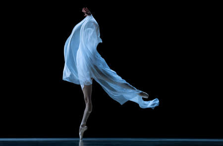 Graceful classic ballerina dancing with weightless fabric isolated on black studio background in neon. Theater, art, beauty, grace, action and motion concept.の写真素材