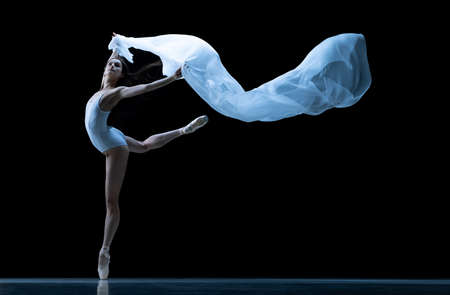Graceful classic ballerina dancing with weightless fabric isolated on black studio background in neon. Theater, art, beauty, grace, action and motion concept.の写真素材