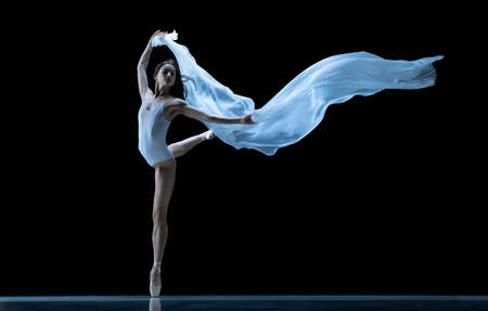 Beauty. Classic ballerina dancing with weightless fabric isolated on black studio background in neon. Theater, art, grace, action and motion concept.の写真素材