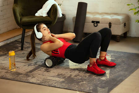 Young attractive sportive girl doing exercises for abs with sport equipment at home, indoors....