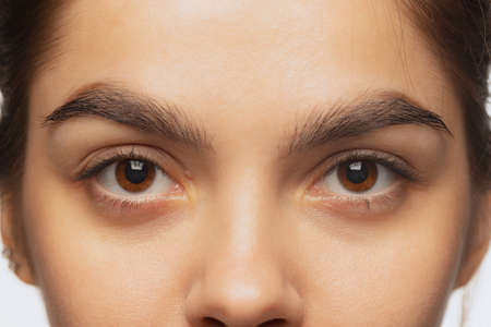 Cropped close-up image of female beautiful brown eyes looking at camera isolated over white studio backgroundの写真素材