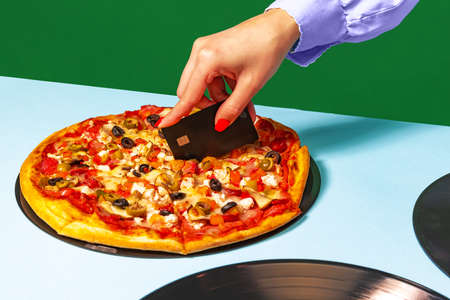 Creative slicing pizza. Female hands with italian pizza lying on vinyl discs on light tablecloth...