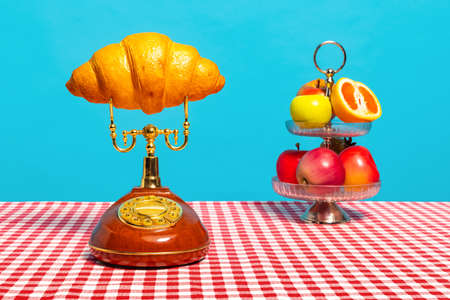 Creative still life with flowers, fruit and retro phone isolated on bright blue red background....