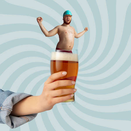 Contemporary art collage. Funny man in swimming cap standing inside foamy lager beer glass isolated over light blue backgroundの写真素材