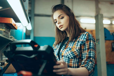 Female auto mechanic, beautiful young girl in working process at auto service station, indoors....