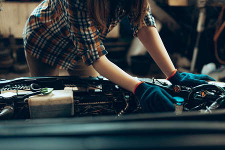 Cropped portrait of female auto mechanic working at auto service station inspecting a car engine. Gender equality. Work, occupation, carの写真素材