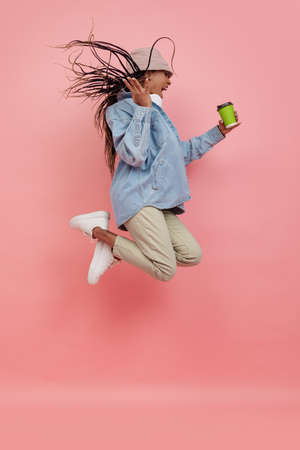 Studio shot of young excited woman in casual style outfit jumping isolated on pink background. Concept of beauty, art, fashion, youth, styleの写真素材