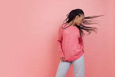 Studio shot of young excited girl with afro hairdo in casual style outfit having fun isolated on pink background. Concept of beauty, art, fashion, youth, styleの写真素材