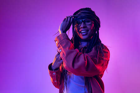 Portrait of female fashion model in cotton shirt isolated on purple background in neon light....