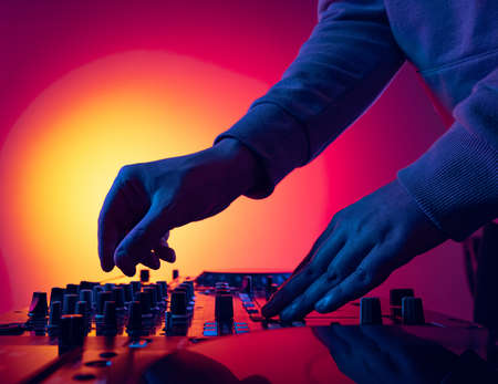 Close-up image of male hands, dj making sounds at night club party with professional sound mixer. Modern party styleの写真素材