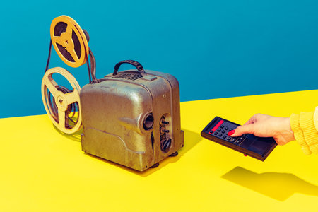 Pop art photography. Colorful image of retro film player on yellow bright tablecloth isolated over...