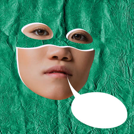 Contemporary art collage. Young seriously looking woman wearing mask of superhero isolated over green background with speech bubbleの写真素材