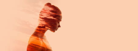 Conceptual image. Silhouette of young transparent woman and sunset landscape isolated over light peach background. Flyerの写真素材