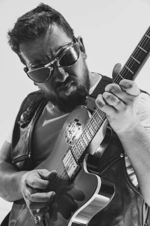 Black and white portrait of stylish man, rock musician with electric guitar isolated on white...
