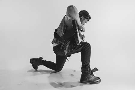 Monochrome. Portrait of stylish young man, rock musician playing electric guitar isolated on white background. Concept of art, music, styleの写真素材