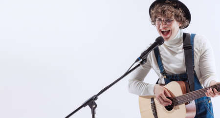 Portrait of young emotiona man, musician playing acoustic guitar and singing. Concept of art, music,...