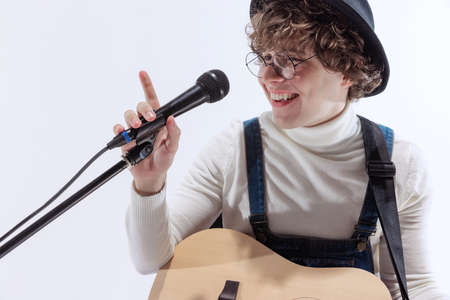 Portrait of young emotiona man, musician playing acoustic guitar and singing. Concept of art, music,...