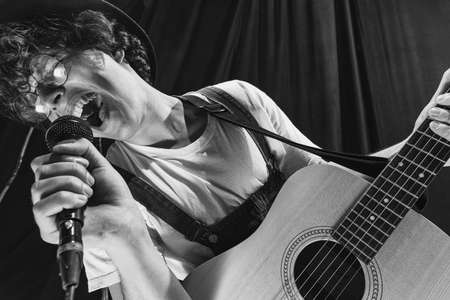 Repetition of retro music band at music studio. Young musician playing acoustic guitar and singing. Rehearsal base. Concept of art, music, style and creationの写真素材