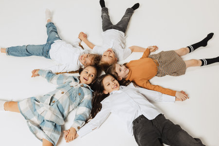 Aerial view of happy smiling school kids lying in circle and looking at camera. Beauty, kids...