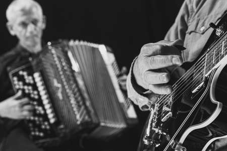 Black and white portrait of two senior men, musicians with guitar and accordion at music studio. Concept of art, music, style and creation. Monochromeの写真素材