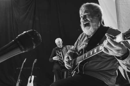 Black and white portrait of two senior men, musicians with guitar and accordion at music studio. Concept of art, music, style and creation. Monochromeの写真素材