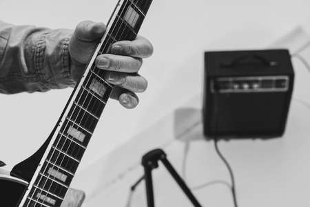 Close-up hands and electric guitar. Cropped monochrome portrait of man, rock musician playing guitar isolated on light background. Concept of music, style, artの写真素材