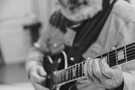 Close-up hands and electric guitar. Cropped monochrome portrait of man, rock musician playing guitar isolated on light background. Concept of music, style, artの写真素材