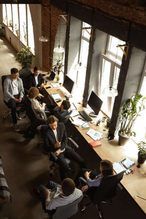 Young people talking, working with colleagues, co-workers at loft style office. Business, urban...