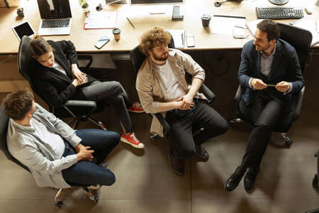 Young people talking, working with colleagues, co-workers at loft style office. Business, urban...