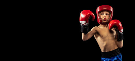 Flyer with sportive boy, kid in boxer gloves and shorts practicing isolated on dark background. Concept of sport, movement, studying, achievements, active lifestyle.の写真素材