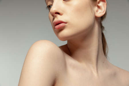 Close-up image of tender female neck, lips and chin isolated over grey studio background. Plastic surgeryの写真素材