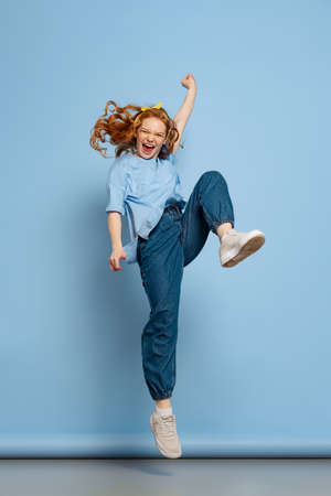 Astonished young redhead girl, student posing isolated on blue studio background. Human emotions, facial expression concept. Trendy colorsの写真素材