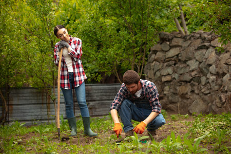 Young and happy farmers couple at their garden in sunny day. Man and woman engaged in the cultivation of eco friendly products. Concept of farming, agricultureの写真素材