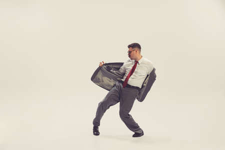 Portrait of young man, businessman dressed in suit in 50s, 60s fashion style dancing isolated on...