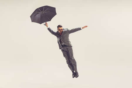Portrait of young man dressed in 50s, 60s style with umbrella isolated on white background. Concept...