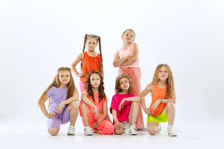 Dance group of happy, active little girls in bright colorful clothes dancing isolated on white studio background. Concept of music, fashion, art, childhood, hobbyの写真素材