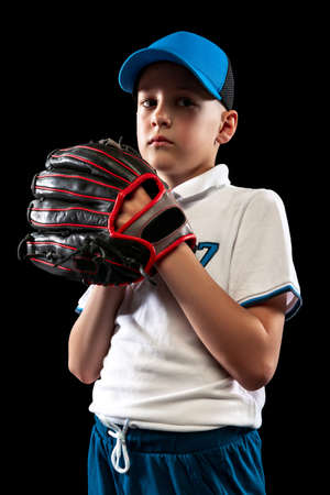 Half-length portrait of kid, beginner baseball player in sports uniform posing with baseball glove isolated on dark background. Concept of sport, achievements, competitionの写真素材