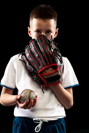 Half-length portrait of kid, beginner baseball player in sports uniform posing with baseball glove...