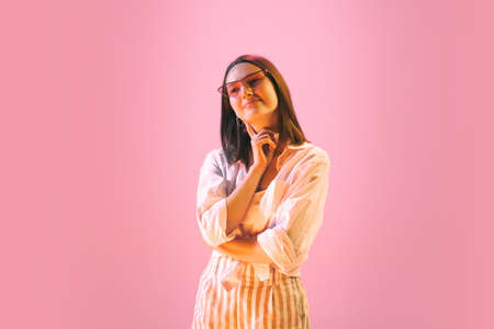 Studio shot of young pretty girl in summer fashion collection outfit posing isolated on pink background. Concept of emotions, facial expression, youthの写真素材