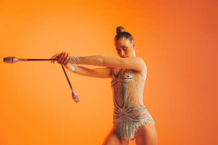 Young flexible woman, rhythmic gymnastics artist performing with clubs isolated on white background. Concept of sport, action, aspirationの写真素材