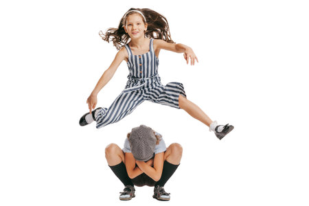 Happy school age kids wearing retro clothes playing leapfrog isolated over white background. Concept of childhood, vintage summer fashion styleの写真素材